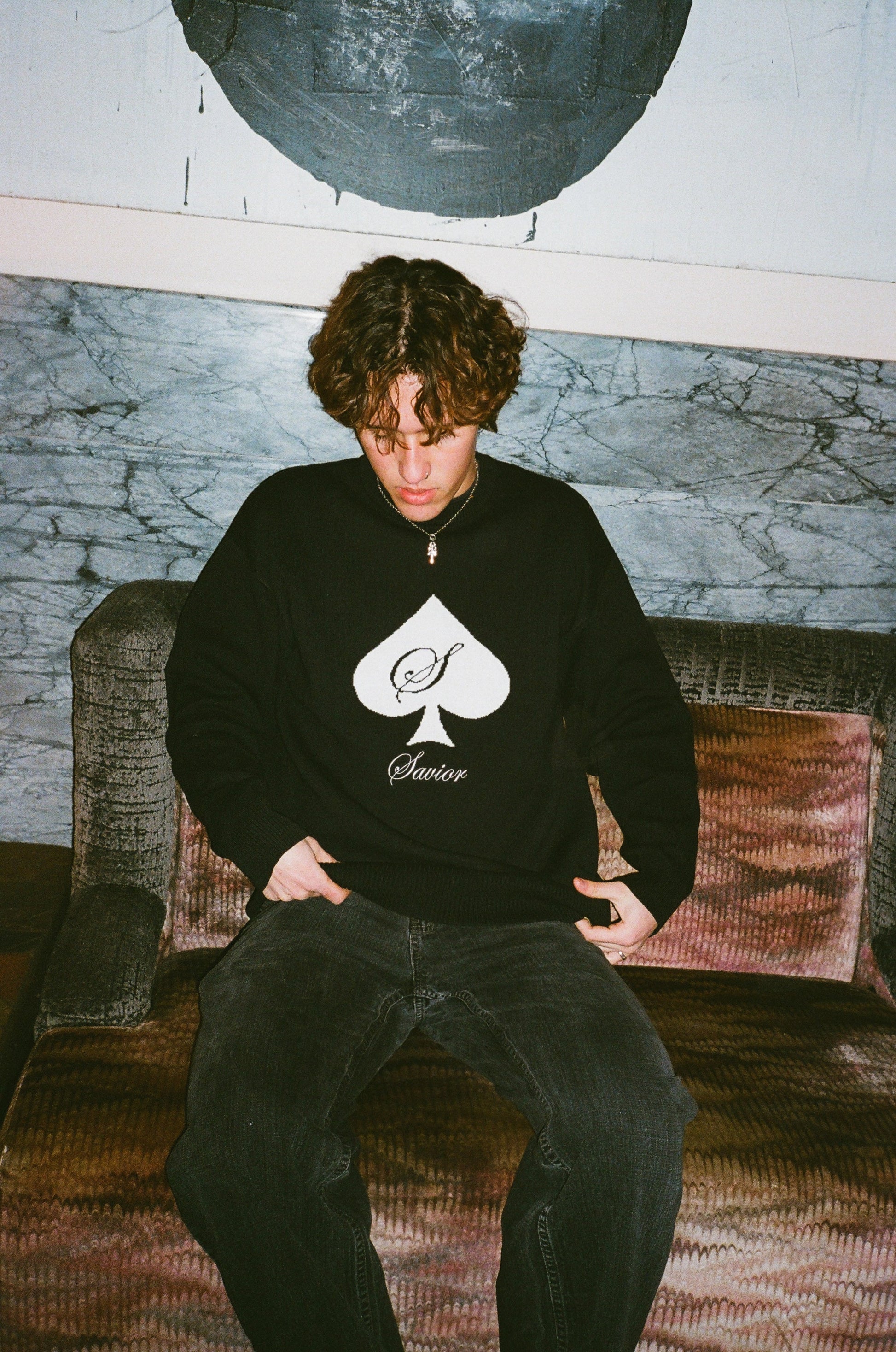 Model wearing SAVIOR Black knit sweater with white spade on it.