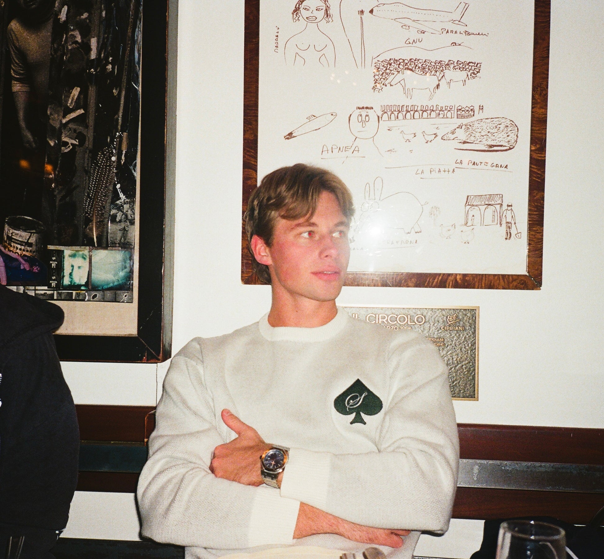 Model wearing a white knit SAVIOR sweater with spade logo